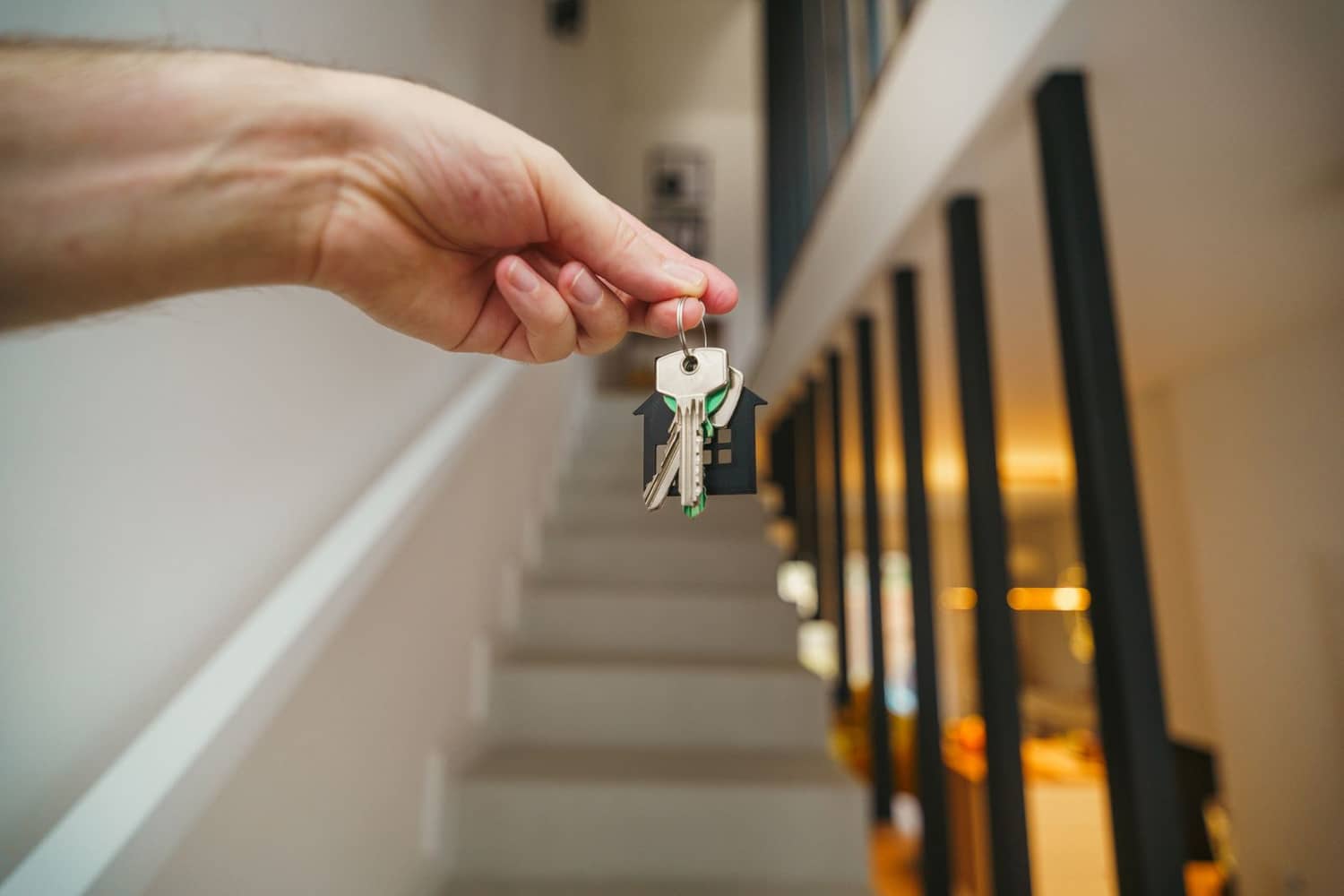 Hand hält Hausschlüssel in modernem Innenraum